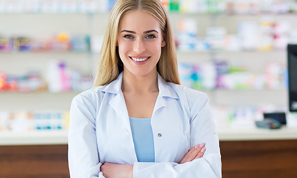 Personne de sexe féminin blonde en manteau de pharmacie blanc se dresse devant l'étagère de la pharmacie